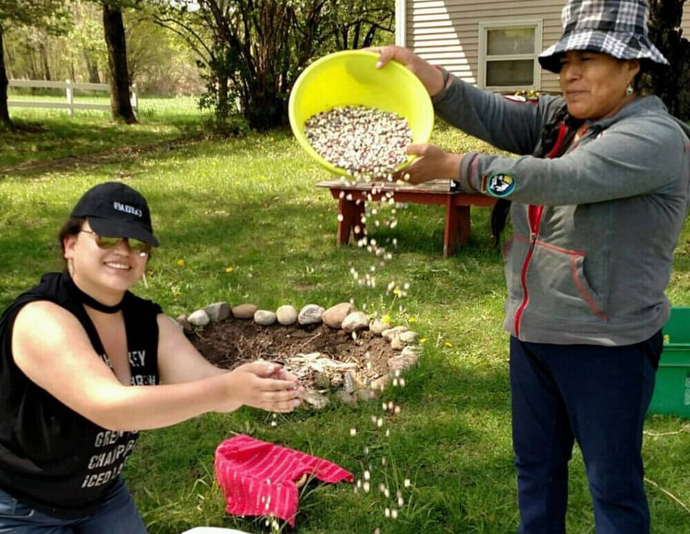 people smiling and pouring a bowl of seeds