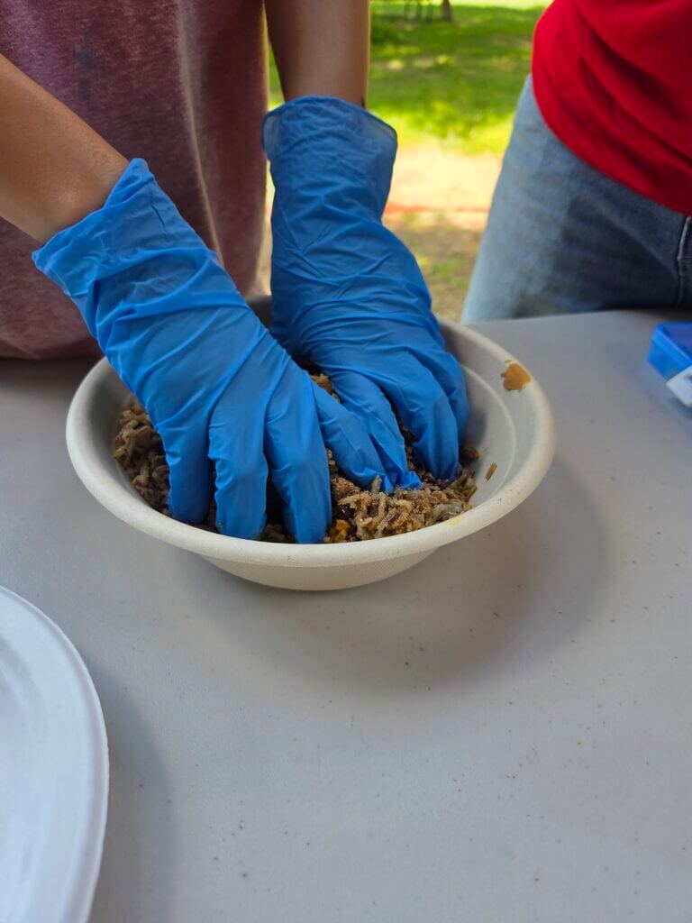 person wearing gloves while preparing food in a bowl outside