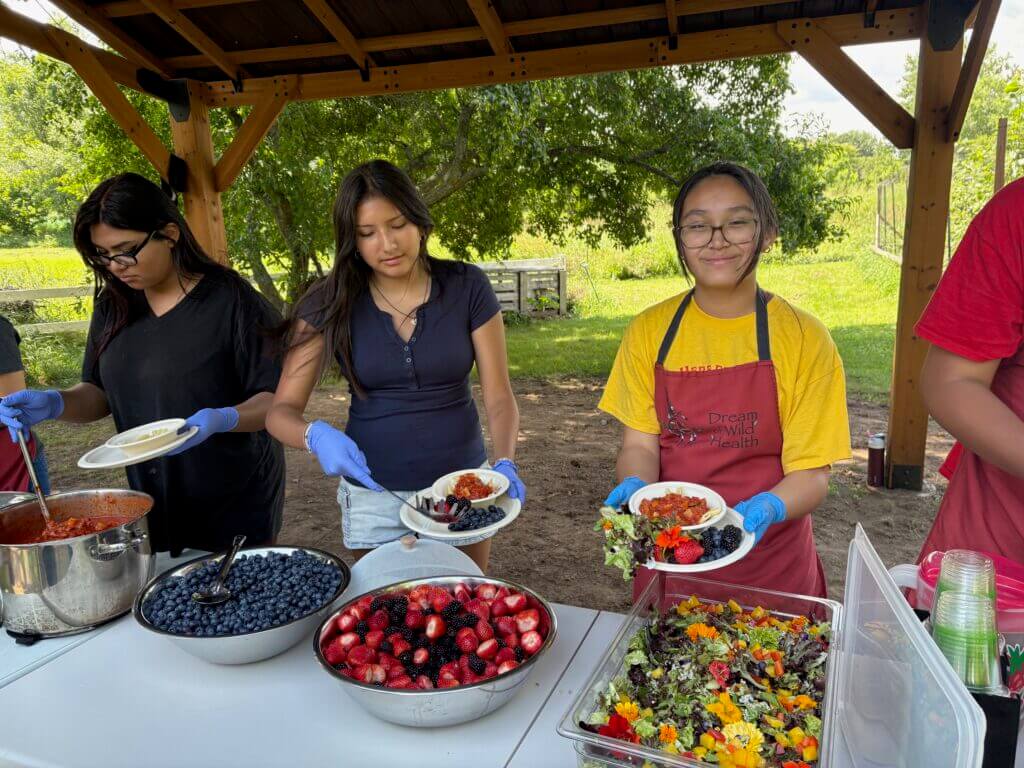 kids smiling and serving fresh, bright food outside